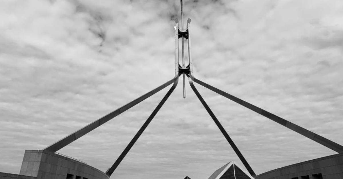 Photo of New Parliament House, representing Australian politics. The photo is of the four beams coming to the roof of the building.